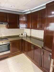 a kitchen with wooden cabinets and a stove at شاطئ المرجان in King Abdullah Economic City +3 photos