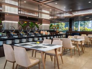 a restaurant with tables and chairs and a bar at Mercure Jakarta Grogol in Jakarta