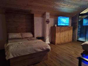 a bedroom with a bed and a flat screen tv at Villa Kristal Slatina- Private Pool & Jacuzzi BBQ in Slatina Varoš