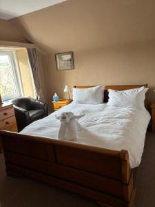 a white dog sitting on a bed in a bedroom at Achness Hotel in Lairg