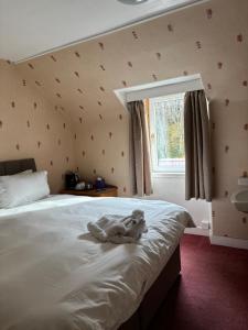 a teddy bear sitting on a bed in a bedroom at Achness Hotel in Lairg