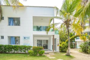 a white building with palm trees in front of it at Cabañas Aqua Blue Coveñas in Coveñas