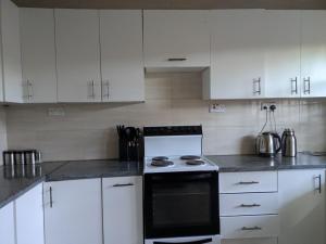 a kitchen with white cabinets and a black stove at Rehoboth Area 49 Guest House in Lilongwe