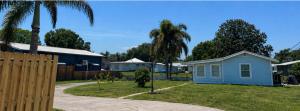 a small blue house in a yard with palm trees at Water front Lake House in Okeechobee