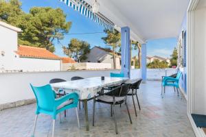 a patio with blue chairs and a white table at Apartments by the sea Maslinica, Solta - 14748 in Maslinica
