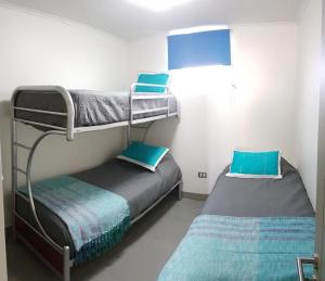 1 dormitorio con 2 literas y almohadas azules en Laguna del Mar Apartamento 208, en La Serena
