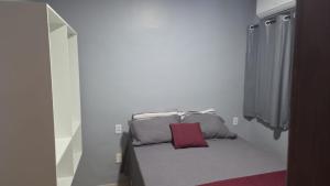 a small bedroom with a bed with a red pillow at pajuçara R2 in Maceió