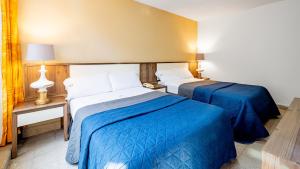 two beds in a hotel room with blue sheets at Hotel Mariscal in Mexico City