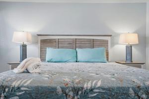 a bedroom with a bed with blue pillows and two lamps at Malibu Resort Motel in St. Pete Beach
