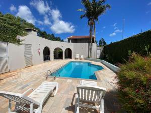 a villa with a swimming pool and two chairs at Blue Suítes - motel in Cascavel