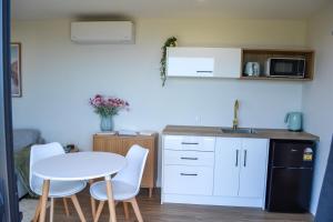 a kitchen with a table and chairs and a sink at Tūhua View Retreat in Waihi Beach +12 photos