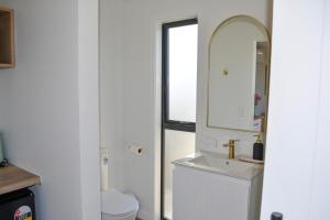 a white bathroom with a sink and a mirror at Tūhua View Retreat in Waihi Beach