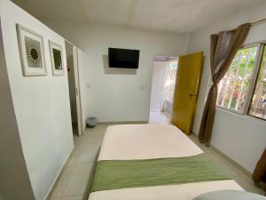 a white room with a bed and a television at La Casa Hostal Vijes in Vijes