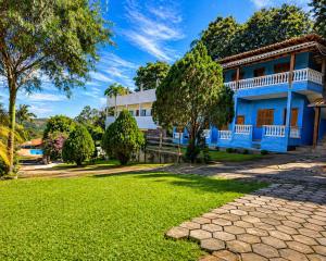 a blue house with a green yard at Pousada Efraim in Tiradentes