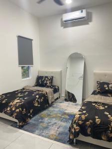 a bedroom with two beds and a tv on the wall at Singgah Salam Stay in Parit Raja