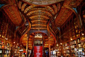 a library with a ceiling with bookshelves and a red staircase at Cativo Flat in Porto