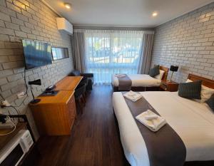a hotel room with two beds and a television at Homestead Motor Inn & Apartments in Bendigo