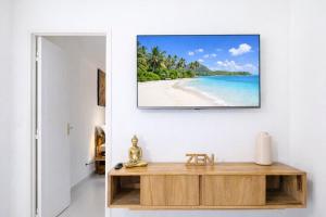 a living room with a table and a picture of a beach at L' É'sens Karaïbes in Les Abymes
