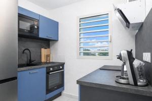a kitchen with blue cabinets and a sink and a microwave at L' É'sens Karaïbes in Les Abymes