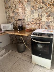 a kitchen with a stove and a counter with a microwave at Apartamento - Vila Isa in Governador Valadares