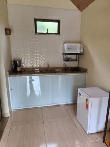 a kitchen with a counter with a microwave and a refrigerator at Chalés Pôr do Sol Alto Caparaó in Caparaó Velho