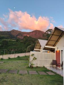 a house with a fence and mountains in the background at Chalés Pôr do Sol Alto Caparaó in Caparaó Velho +23 photos