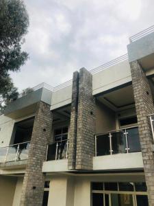 a large building with a balcony and a cloudy sky at Ni HOME & RELAX in Ruhengeri +2 photos