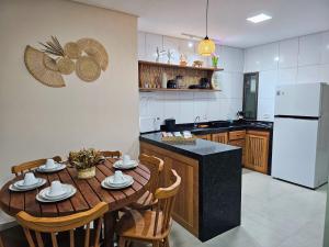 a kitchen with a wooden table with chairs and a refrigerator at Casas Costa Dos Corais - 200m do mar, Climatizada, Confortável e Completa in Japaratinga +31 photos