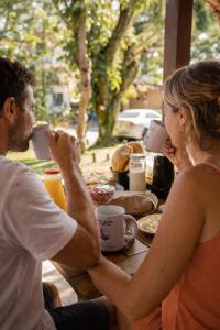 a man and woman sitting at a table drinking coffee at Morada Quatro Elementos - 150 Metros do Centrinho in Praia do Rosa