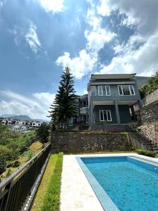 a house with a swimming pool in front of a house at Al Andalus Resort Puncak in Puncak
