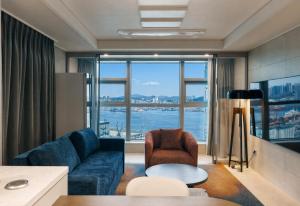 a living room with a blue couch and a large window at Matie Busan Harbor City in Busan