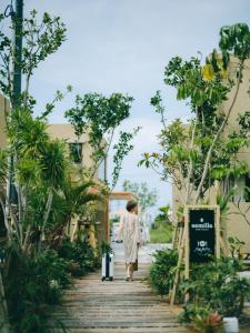 a woman walking down a wooden walkway at semilla 名護 沖縄 in Nago
