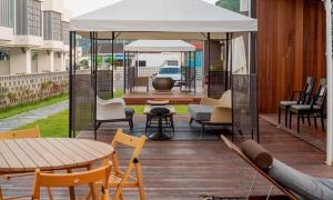 a deck with chairs and tables and a white canopy at Aldea de Pangsion Pool Villa in Pohang