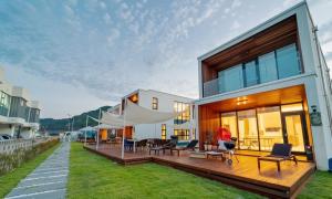 a house with a deck with chairs and tables at Aldea de Pangsion Pool Villa in Pohang