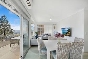 a dining room with a table and chairs and a couch at Blue Pacific Apartment 8 in The Entrance