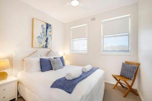 a bedroom with a white bed and two windows at Blue Pacific Apartment 8 in The Entrance
