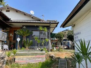 a house with palm trees in front of it at Norishicoauto Guesthouse in Chikushino