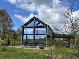 a glass pavilion with a bench in a park at Modern design house with sauna 'Arduenna Silva' in La-Roche-en-Ardenne