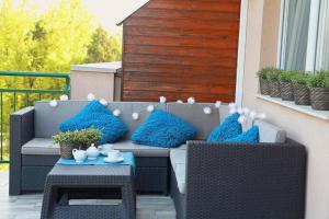a patio furniture with blue pillows on a balcony at Monarchia Apartman Sunny in Mosonmagyaróvár +10 photos