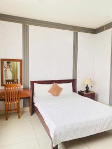 a bedroom with a bed and a desk and a chair at NGỌC MẤY - ĐẠI LỢI HOTEL in Chau Doc +24 photos