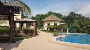 a resort with a swimming pool next to a house at The Halfway Cafe-Dauin, Glamp1 - Cricket in Dauin