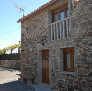 kamienny dom z drewnianymi drzwiami i oknem w obiekcie A Casa de Sergio w mieście Mazaricos