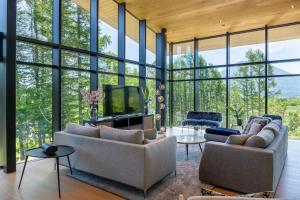 a living room with couches and a tv and windows at Kazahana at Hanaridge in Kutchan