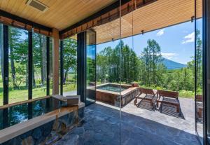 a glass house with a hot tub and a patio at Kazahana at Hanaridge in Kutchan