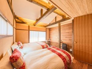 two beds in a room with wooden ceilings at 縁や出雲 in Taisha