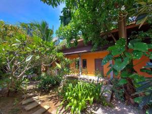 an orange house with trees and plants in front of it at Six Pack Cottage in Chalong