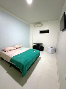 a bedroom with a bed with a green blanket at Quarto privado próximo ao centro 3 in Manaus