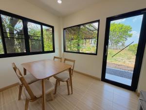 a dining room with a table and chairs and windows at Four Moon Khaoyai in Pong Talong