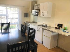 a kitchen with white cabinets and a table and chairs at Twin Coast Adventures Motel & Cycle Hire in Kaikohe