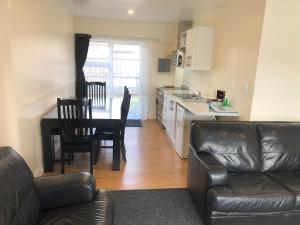 a living room with a couch and a table and a kitchen at Twin Coast Adventures Motel & Cycle Hire in Kaikohe